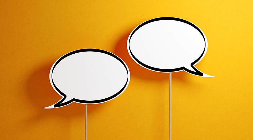 White chat bubbles with wooden sticks on yellow background. Horizontal composition with copy space.